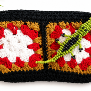 Kaimana handmade black crochet clutch with red, white and ochre granny squares and green beaded crocodile