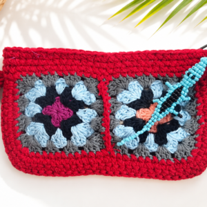 Coral handmade red crochet clutch with colourful granny squares and turquoise beaded gecko
